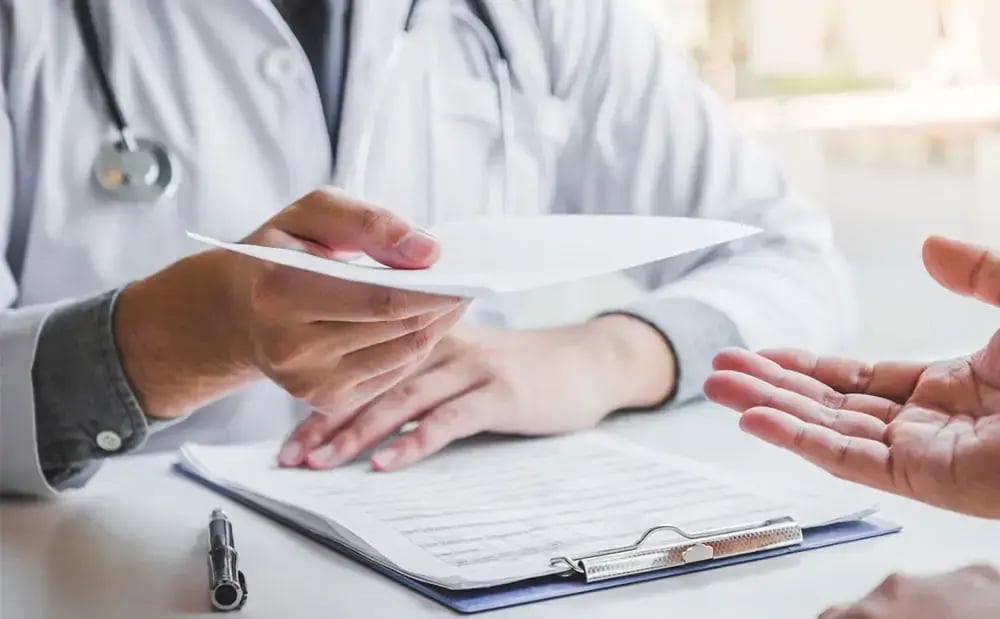 Profissional da saúde entregando um atestado para um colaborador após a consulta